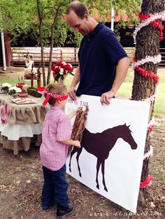 a man standing next to a little boy in front of a horse cut out on a sign