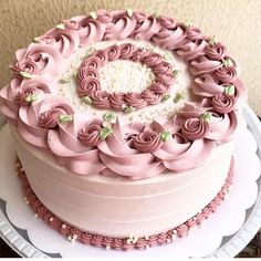 a cake with pink frosting and flowers on top is sitting on a white plate