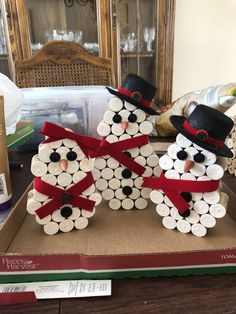 two snowmen made out of wine corks sitting on top of a cardboard box