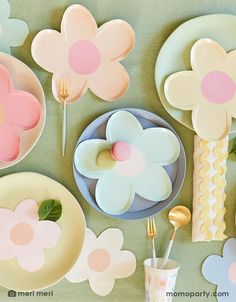 a table topped with plates and flowers next to utensils