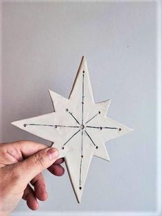 a hand holding a white wooden star ornament