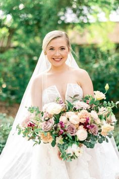 a woman in a wedding dress is holding a bridal bouquet and smiling at the camera