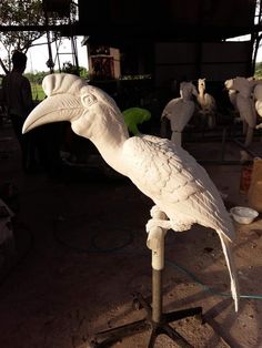 a large white bird sitting on top of a wooden stand