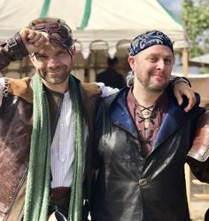 two men in leather jackets and bandanas posing for the camera with their arms around each other