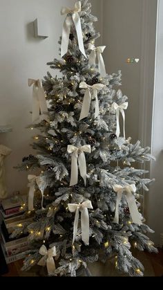 a white christmas tree with bows and lights