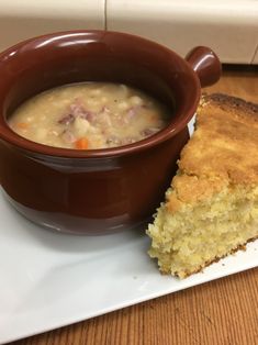 a brown bowl filled with soup next to a piece of bread