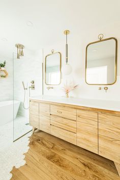 a bathroom with wooden cabinets and two mirrors on the wall next to a bathtub