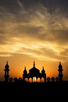 the sun is setting behind an ornate building