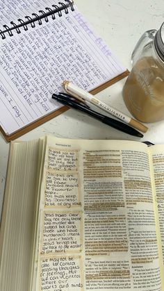 an open book with writing on it next to a cup of coffee and a pen