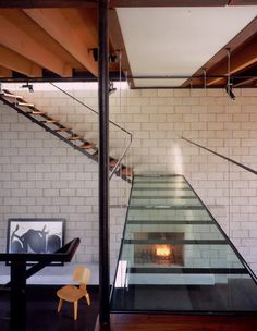 the stairs lead up to the second floor in this modern house with brick walls and glass railings