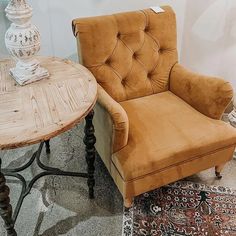 a brown chair sitting next to a wooden table on top of a carpeted floor