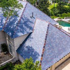 an aerial view of a house with a pool in the back ground and trees surrounding it