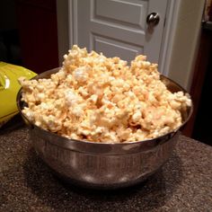 a metal bowl filled with popcorn sitting on top of a counter next to a door