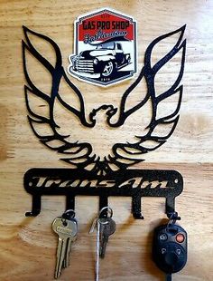 a metal key holder with two keys hanging from it's side and an eagle emblem on