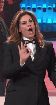 a woman in a tuxedo is making a funny face while standing on stage