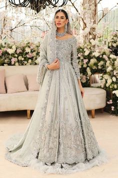 a woman standing in front of a chandelier wearing a grey gown and veil