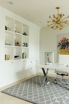 a white desk and chair in a room with bookshelves on the wall behind it