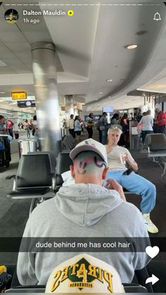 a man sitting in an airport with his face painted like a bird and the caption reads, dude behind me has cool hair