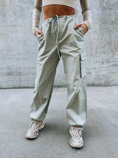 DETAILS: Our Logan Athletic Cargo Pant have an oversized fit with a soft nylon fabric. These cute bottoms have a ribbed stretchy band for a comfortable fit around the waist and there is also a self tie string to synch the waist. There are two side pockets, one flap pocket on the pant leg, and the bottom of the pants have a self tie string to synch it tighter around the ankle. Runs true to size but has an oversized look. CONTENT & CARE: SELF: 100% Polyester. SIZE & FIT: Model is 5'6" The model is wearing a size s/m. This has an oversized fit. The Fabric has no stretch Outdoor Stretch Pants With Drawstring, Utility Sweatpants With Drawstring For Loungewear, Utility Style Drawstring Sweatpants For Loungewear, Casual Parachute Pants With Functional Drawstring For Spring, Spring Cargo Style Sweatpants, Utility Drawstring Sweatpants For Loungewear, Spring Solid Color Cargo Sweatpants, Trendy Solid Bottoms With Tie Waist, Stretch Khaki Pants With Drawstring