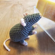 a crocheted mouse sitting next to a piece of cheese