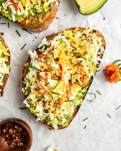 two pieces of toast with different toppings on them next to an avocado