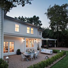 a white house with lots of windows and lights on the front door, patio area