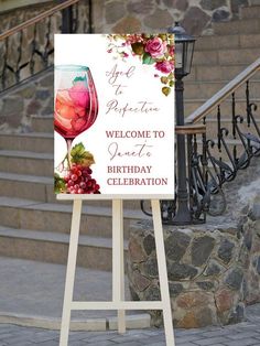 a welcome sign with a glass of wine on it next to some stairs and stone steps