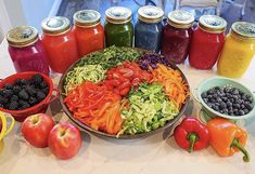 a table topped with lots of different types of fruit and veggies next to jars