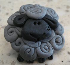 a black and grey sheep with spirals on it's head sitting on a table