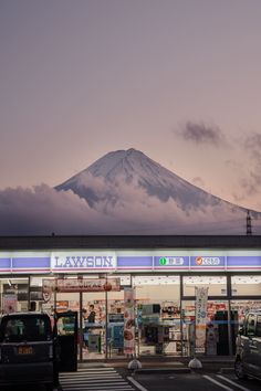 a car parked in front of a store with a mountain in the backgroud