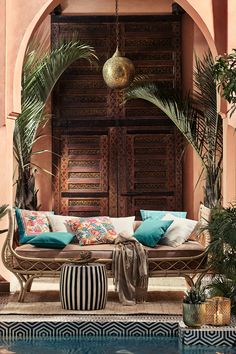 a couch sitting next to a pool in front of a wooden door with palm trees