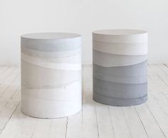 two white and grey marble side tables sitting next to each other on a wooden floor