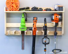 several different types of tools are hanging on a wall above a wooden shelf with hooks and pegs