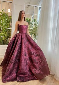 This exquisite maroon bordeaux dress is the epitome of timeless elegance and modern sophistication. Crafted from a rich tapestry of brocade fabric, it's accented with delicate organza for an ethereal touch. The bodice is a masterpiece of design, meticulously structured with full boning to contour and flatter the figure, complemented by a strapless neckline that adds a touch of classic allure. The dress cascades into a stunning A-line silhouette, featuring a full, dramatic skirt that promises to Ball Gown Unique, Plum Ball Gown, Prom Dresses Dramatic, Ball Gown Dresses Elegant, Dramatic Ball Gowns, Ball Gowns Long Sleeve, Fantasy Ball Gowns, Unique Ball Gowns, Teuta Matoshi Dresses