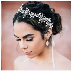 a woman wearing a bridal headpiece with flowers and leaves on it's hair