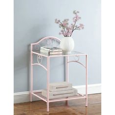 a white vase with flowers sitting on top of a pink metal shelf next to a wall