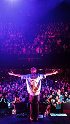 a man standing on top of a stage in front of a large group of people