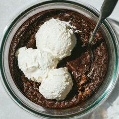 two scoops of ice cream sit in a bowl with brownie and whipped cream