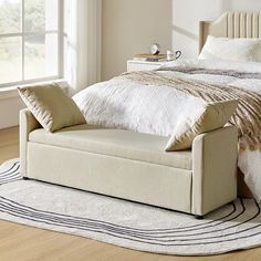 a white bed sitting on top of a hard wood floor next to a large window