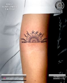 a sunflower tattoo on the arm with leaves and flowers around it's center