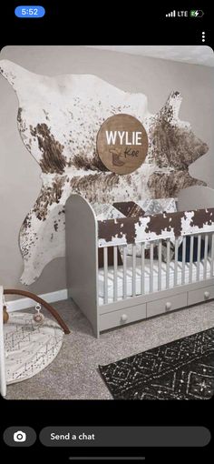 a baby's room with a cow theme on the wall and white crib