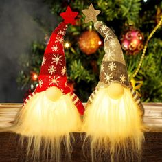 two gnome hats sitting on top of a wooden table next to a christmas tree with lights