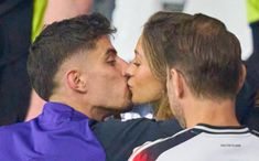 a man and woman kissing each other at a soccer game