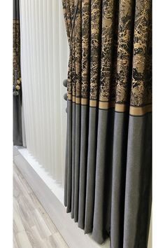 the curtains are lined up in front of the window with black and gold designs on them