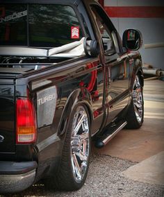 a black truck with chrome rims parked in front of a building