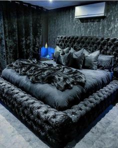 a large bed in a room with black walls and carpeted flooring, along with two lamps on either side of the bed