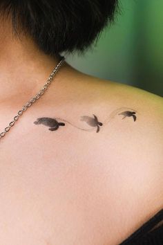 the back of a woman's shoulder with three small birds on her left side