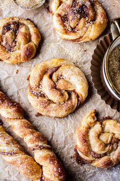 freshly baked cinnamon rolls on parchment paper next to a bowl of powdered sugar and spoon