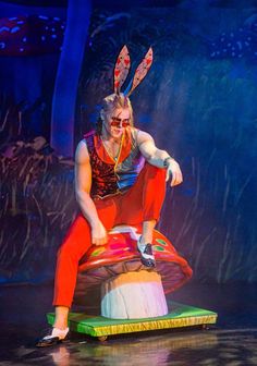 a man in bunny ears sitting on top of a mushroom shaped object at the circus