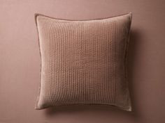 a brown pillow sitting on top of a pink wall